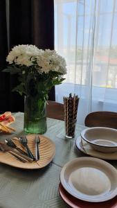 贾塞尼采Apartmani Masline的一张桌子,上面有盘子和白色花瓶