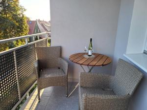格但斯克Apartament nad morzem的阳台上配有一张桌子和两把椅子,并提供一瓶葡萄酒
