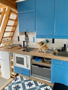 多维尔Studio Mezzanine La vie en bleu- Vue mer Deauville的厨房配有蓝色橱柜和微波炉
