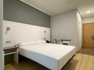 维戈Hotel Arsus的卧室配有一张白色大床和一张书桌