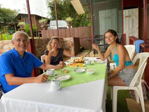 图里亚尔瓦Bella Vista Ranch Ecolodge的三人坐在餐桌上吃着食物
