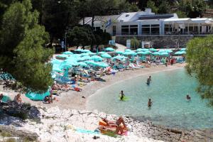 木洛希尼Apartments by the sea Mali Losinj, Losinj - 19959的一群人,在海滩上,用蓝伞