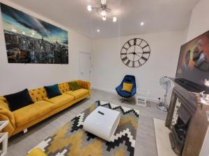 芬奇利Garland Modern 4 Bedroom Central Apartment London的客厅配有黄色沙发和时钟