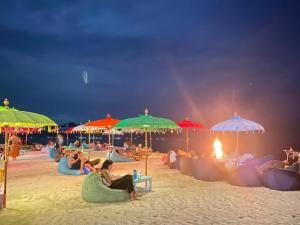 吉利阿尔吉利郎邦简易别墅的一群人坐在海滩上,在遮阳伞下