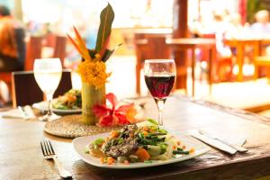 纳玛塔库拉芒果湾度假村的一张桌子,上面放着一盘食物和一杯葡萄酒