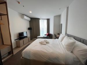 芭堤雅市中心Edge Central Pattaya Condo的酒店客房设有白色的床和电视。