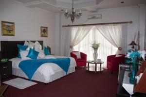 Mohales HoekHotel Mount Maluti - Lesotho的一间卧室配有一张床和两张红色椅子