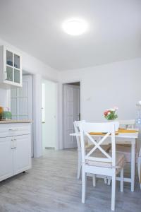 毛科Jázmin Apartman的白色的厨房配有白色的桌子和椅子