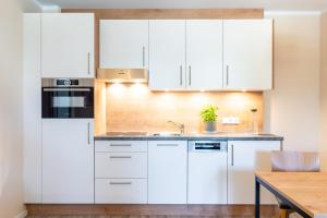 格拉尔-米里茨Ostsee Apartmenthotel的厨房配有白色橱柜和木桌