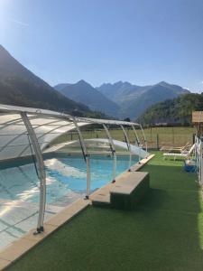 SaligosCamping Happy Pyrénées的一座带金属华盖和绿色草地的游泳池