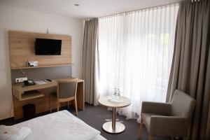 迪尔门泰克斯密尔酒店-餐厅的配有一张床、一张书桌和一扇窗户的酒店客房