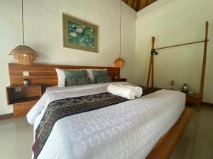 吉安雅Umah Nik Kepitu的一间卧室配有一张大床和木制床头板