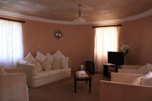 Mohales HoekHotel Mount Maluti - Lesotho的客厅配有白色沙发和电视