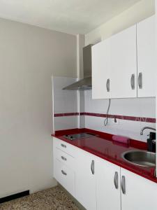 圣克鲁斯-德拉帕尔马罗卡玛酒店的厨房配有白色橱柜和红色台面