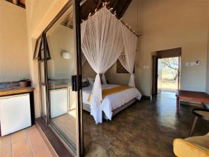 帕拉博鲁瓦Masorini Bush Lodge的一间卧室配有一张带天蓬的床