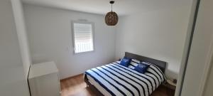 La ChevrolièreLA THOMASERIE的一间卧室配有一张蓝色和白色条纹的床