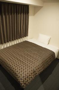 京都京都站前卓越酒店的一间卧室配有一张带棕色毯子的床