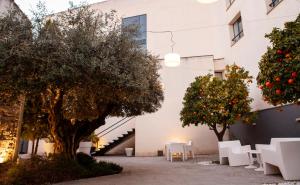 乌贝达YIT El Postigo的建筑前的庭院,庭院里摆放着白色的椅子和树木