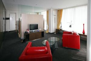 巴特塞格贝格维达利亚海滨酒店的客厅配有2把红色椅子和电视