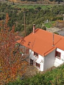 VamvakoúMagnolia Traditional Stone House in Vamvakou的山坡上一座白色房子,屋顶橙色