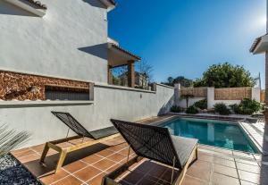 贝莱斯德韦瑙达利亚Villa Blanca - Granada Coast的一个带两把椅子的庭院和一个游泳池