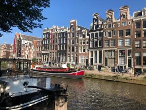 阿姆斯特丹Canal Hideaway的两艘船停靠在运河上,运河上建有建筑物
