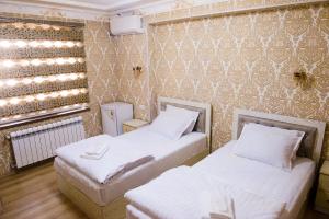 撒马尔罕Durdona Guest House的一间设有两张床和一面墙壁的房间