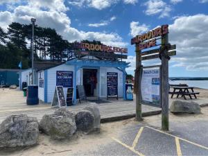 浦耳Cosy, coastal themed Holiday Home, Rockley Park, Poole, Dorset的海滩上的海鲜棚屋,前面有岩石