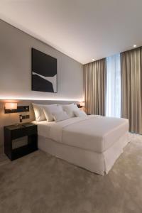 迪拜Lusso Hometels J One Business Bay的一间白色的大卧室,配有一张大床和一张书桌
