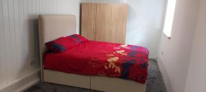 罗瑟勒姆Lovely 3-Bed Apartment in Parkgate Rotherham的一间卧室配有一张带红色棉被的床和一台冰箱