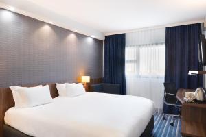 维特罗勒马赛普罗旺斯区机场基里亚德酒店的酒店客房设有一张大床和一张书桌。