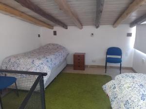 图努扬VILLA DE MONTAÑA LOS CHACAYES, Manzano Hitorico, Caminos del vino, ruta 94的一间卧室配有两张床和一张蓝色椅子