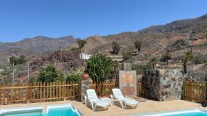 圣卢西亚casa rural LA LIMERA con piscina privada的一个带椅子的庭院和一个背景为山脉的游泳池