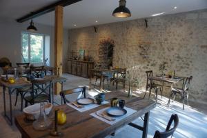 NazellesLe Moulin de Moquesouris - Chambres d'hôtes et table d'hôte的餐厅设有木桌和椅子,拥有砖墙