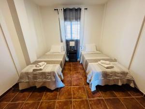 厄尔梅达诺Vista Marina - El Medano Beach的客房内设有两张床,铺有瓷砖地板,设有窗户。