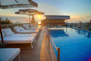 斯卡拉卡里拉奇斯Anny Residences & Suites的酒店游泳池设有白色的床和遮阳伞