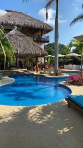 特隆戈内斯Hotel Bajito Bay的一座带茅草建筑的大型游泳池的度假村