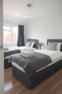 SurbitonKnollmead House的卧室设有两张床,拥有白色的墙壁和木地板