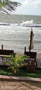 科鲁里皮Vila Bello Pontal的两个长椅和一个伞,靠近海洋
