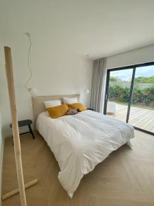 LandunvezMagnifique villa avec piscine, à 5 min des plages的卧室配有白色的床和大窗户