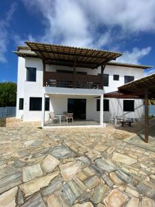 阿拉卡茹Exclusiva Casa na Melhor Praia de Aracaju的一座白色的大建筑,设有石头庭院