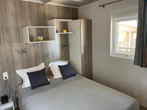 维琪奥港Camping La Baie des Voiles的一间卧室配有带两个枕头的床和窗户