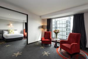 奥克兰SkyCity Hotel Auckland的酒店客房配有一张床、两把椅子和镜子