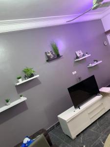 科托努Peaceful Stay 1SR的一间客厅,在紫色的墙上配有电视