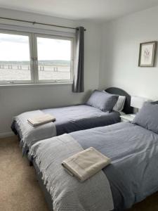 邓迪Lux Waterfront 2 bed Apt, V&A 10min walk, St Andrew's Golf 25min drive的一间卧室设有两张床和一个带海滩的窗户。
