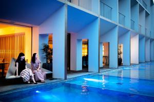 佐贺市Garden Terrace Saga Hotel & Resorts的两个女人坐在游泳池旁边的沙发上