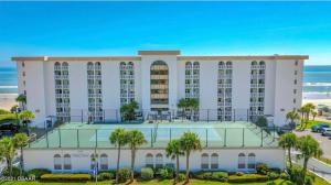 代托纳海滩Beach Oasis 704 Lovely Daytona ocean front for 5 sleeps up to 12的一座大型白色建筑,在海洋前方种有棕榈树