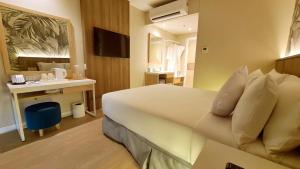 马尼拉Harolds Evotel Quezon City的酒店客房设有一张大床和一张书桌。