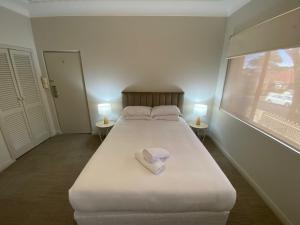 卧龙岗Normandie Wollongong的一间卧室配有一张带两盏灯的大型白色床。