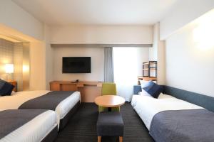 冈山HOTEL MYSTAYS Okayama的一间酒店客房,设有两张床和电视